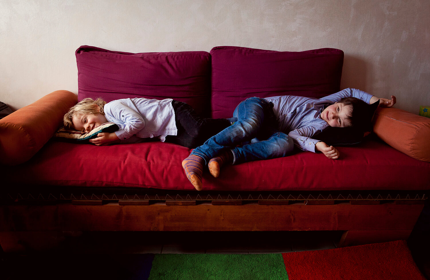 due fratelli sdraiati su sofa rosso