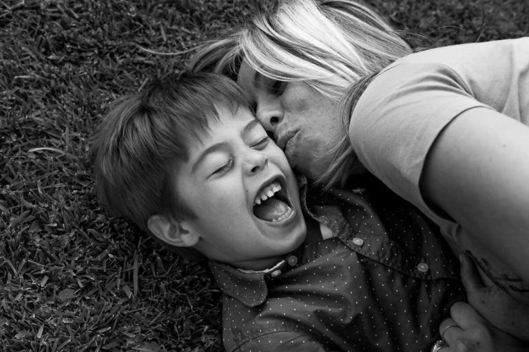 boy kid laying on the grass laughing with mother