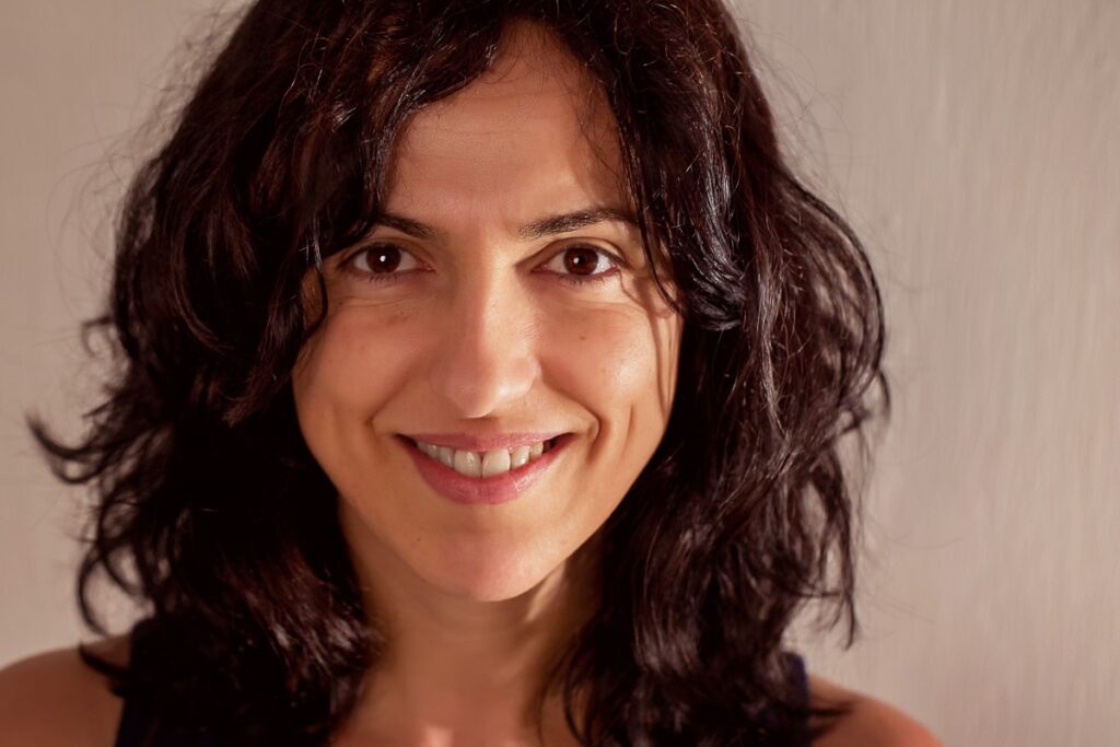 headshot in warm colors of woman with black curly hair