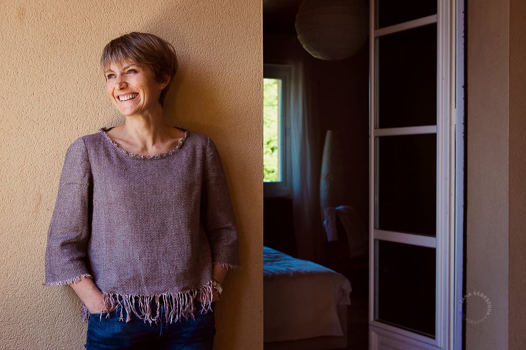 woman is laughing on the balcony leaning on the yellow wall