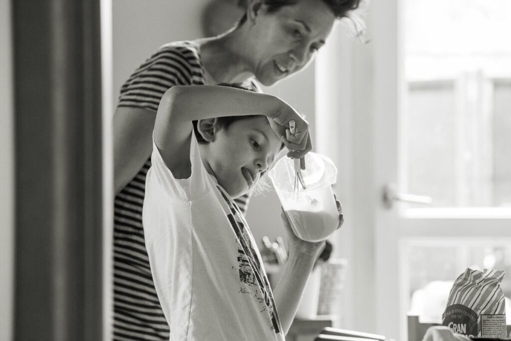 documentary family photoshoot little boy is preparing shaking a milk while mother is watching