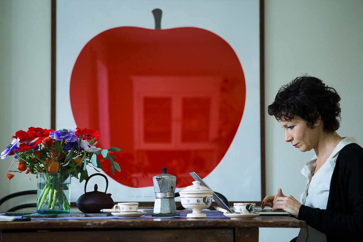 donna seduta al tavolo di fronte a quadro con grande mela