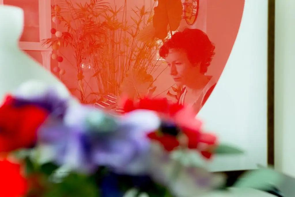 ritratto di donna riflessa nel quadro rossa con fiori sfocati in primo piano
