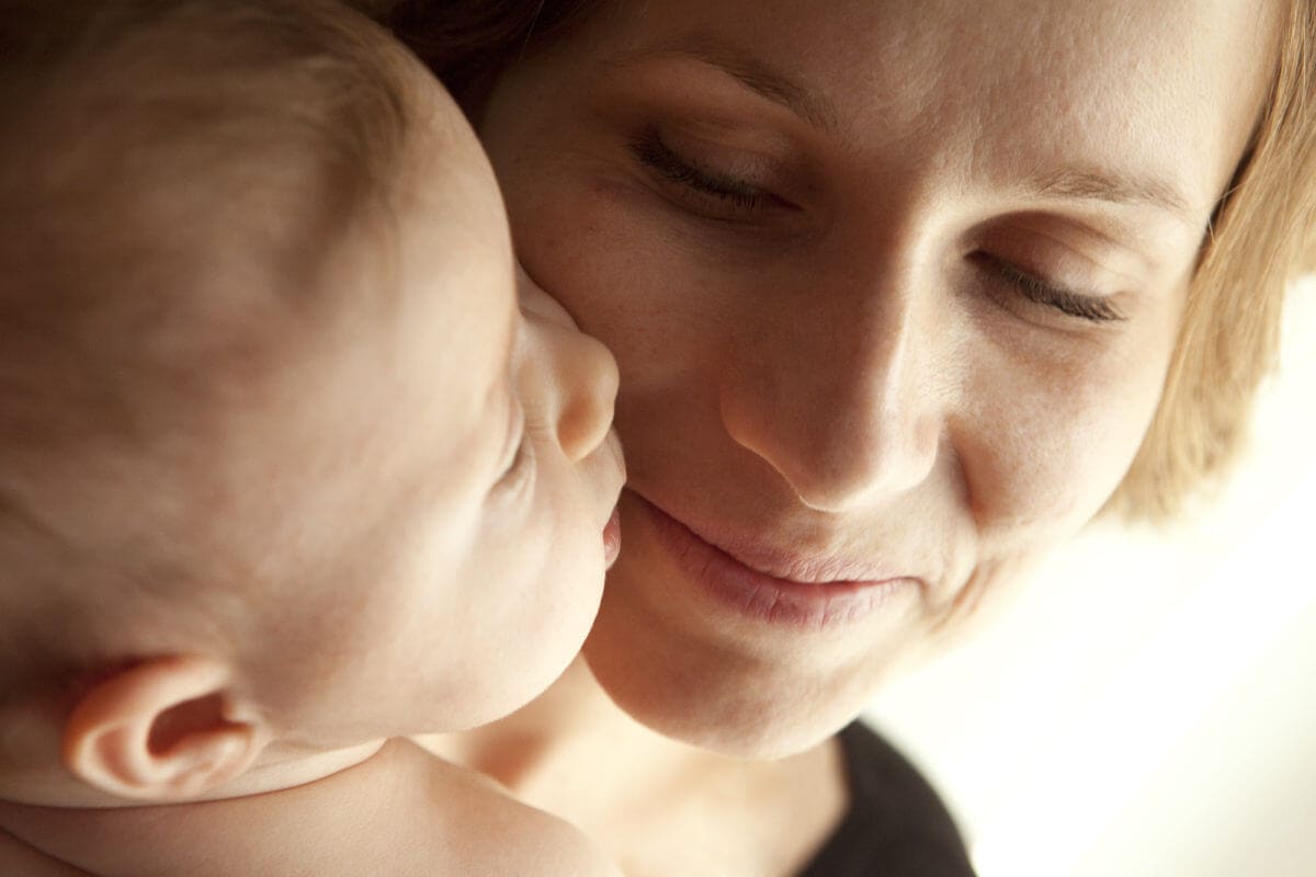 viso di mamma che sorride al piccolo bebe che le da bacio
