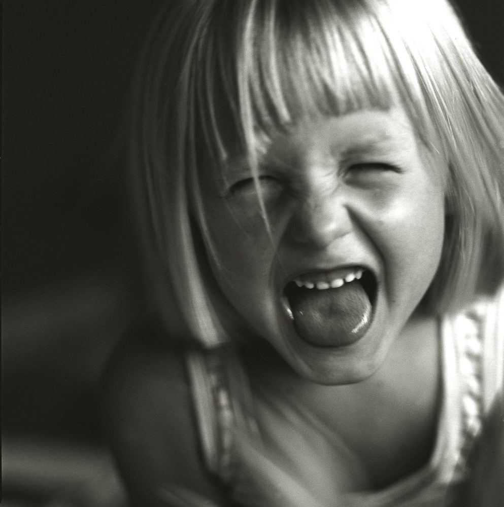 bambina bionda con lingua fuori e viso furioso