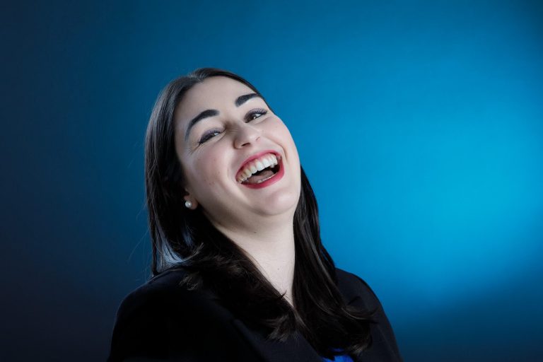 donna con capelli neri lisci ritratta in studio mentre fa una risata