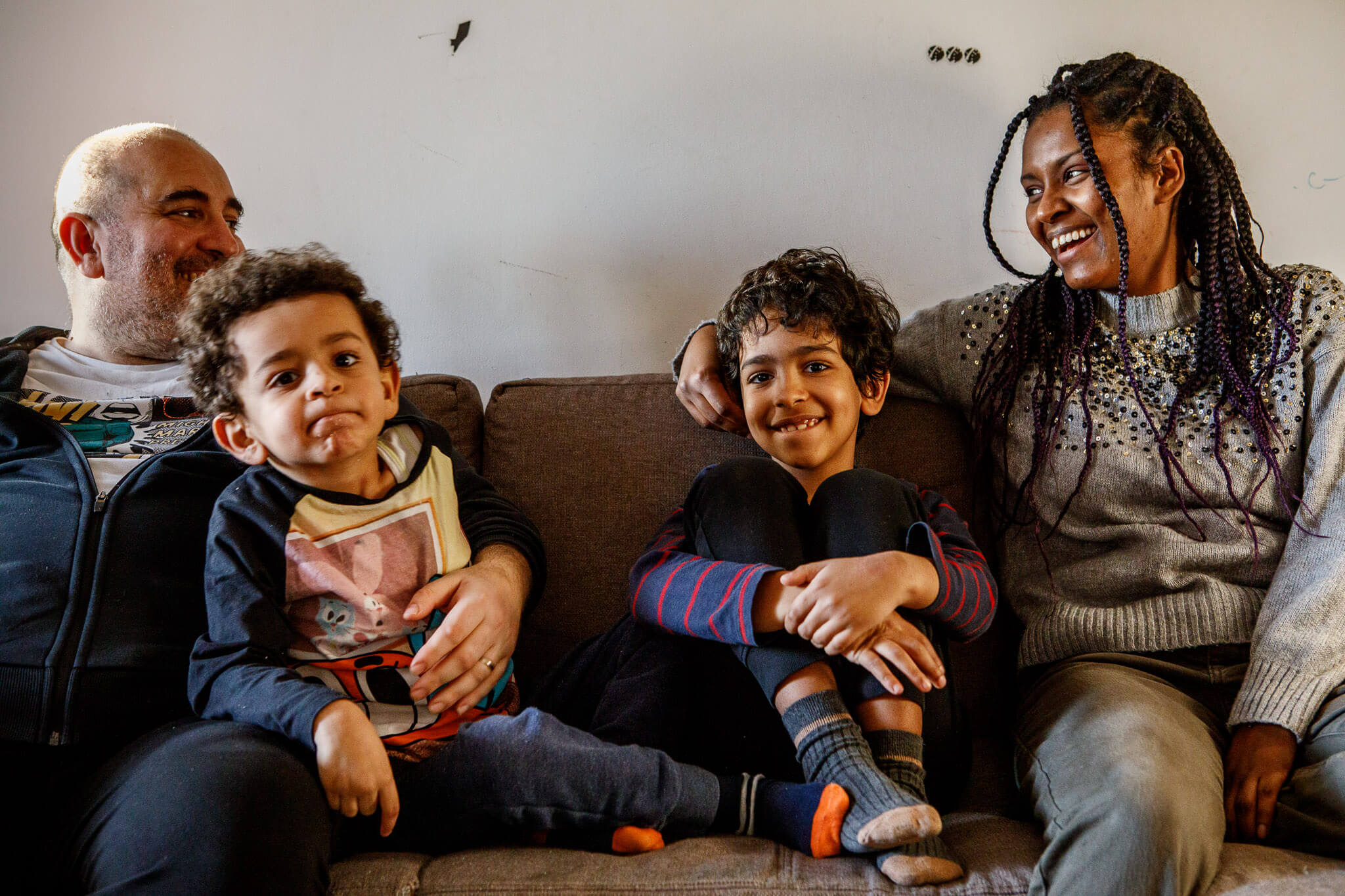 famiglia multietnica con due bambini rilassata sul divano di casa