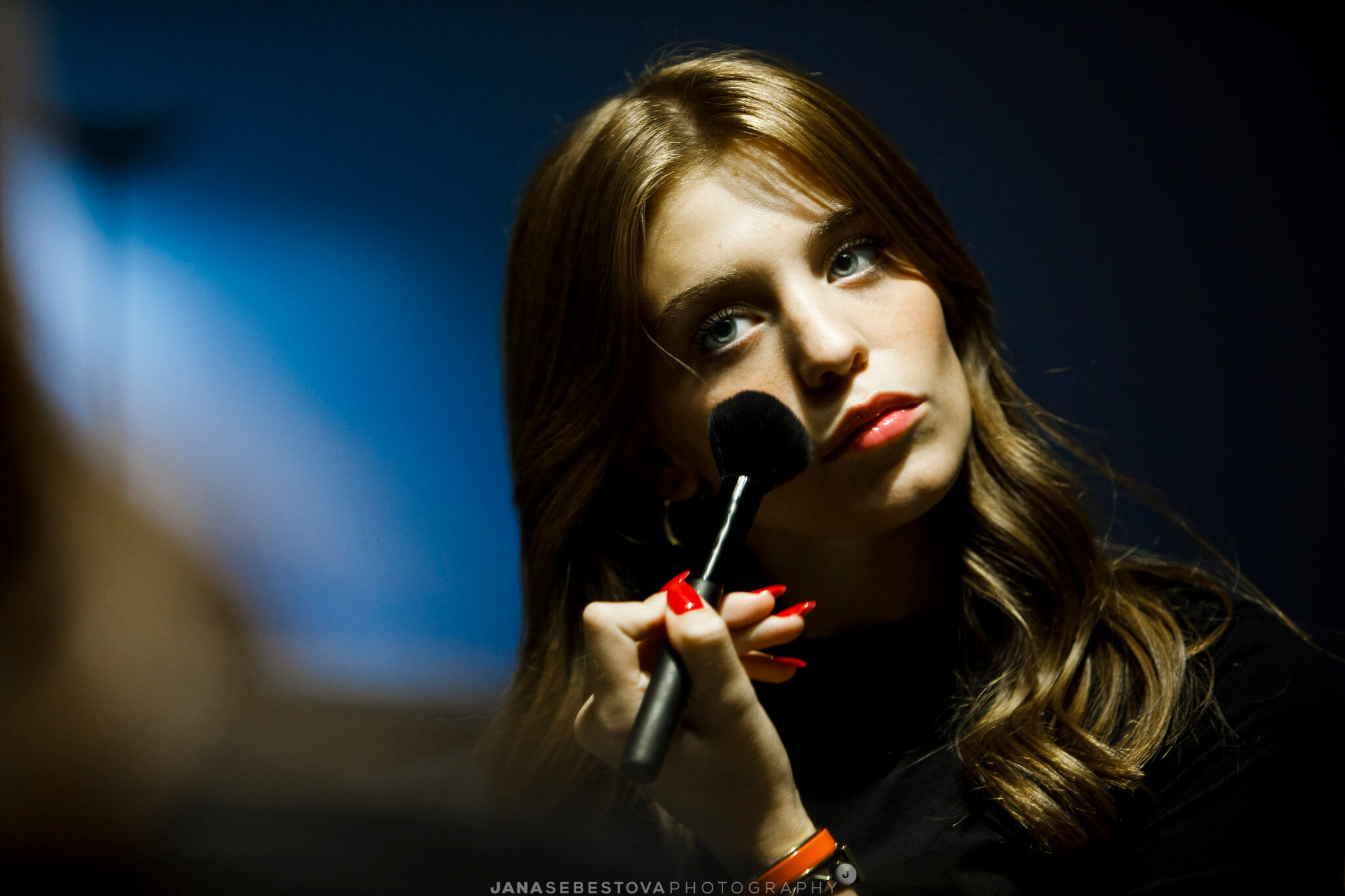 foto donna giovane riflessa nello specchio mentre si trucca con luce chiaro scuro
