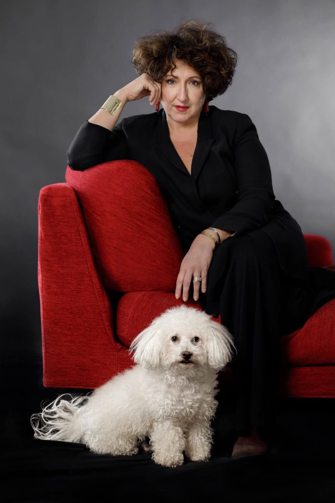 ritratto professionale di avvocata zurigo per suo sito web, vestita di nero seduta su divano rosso con il suo cane bianco