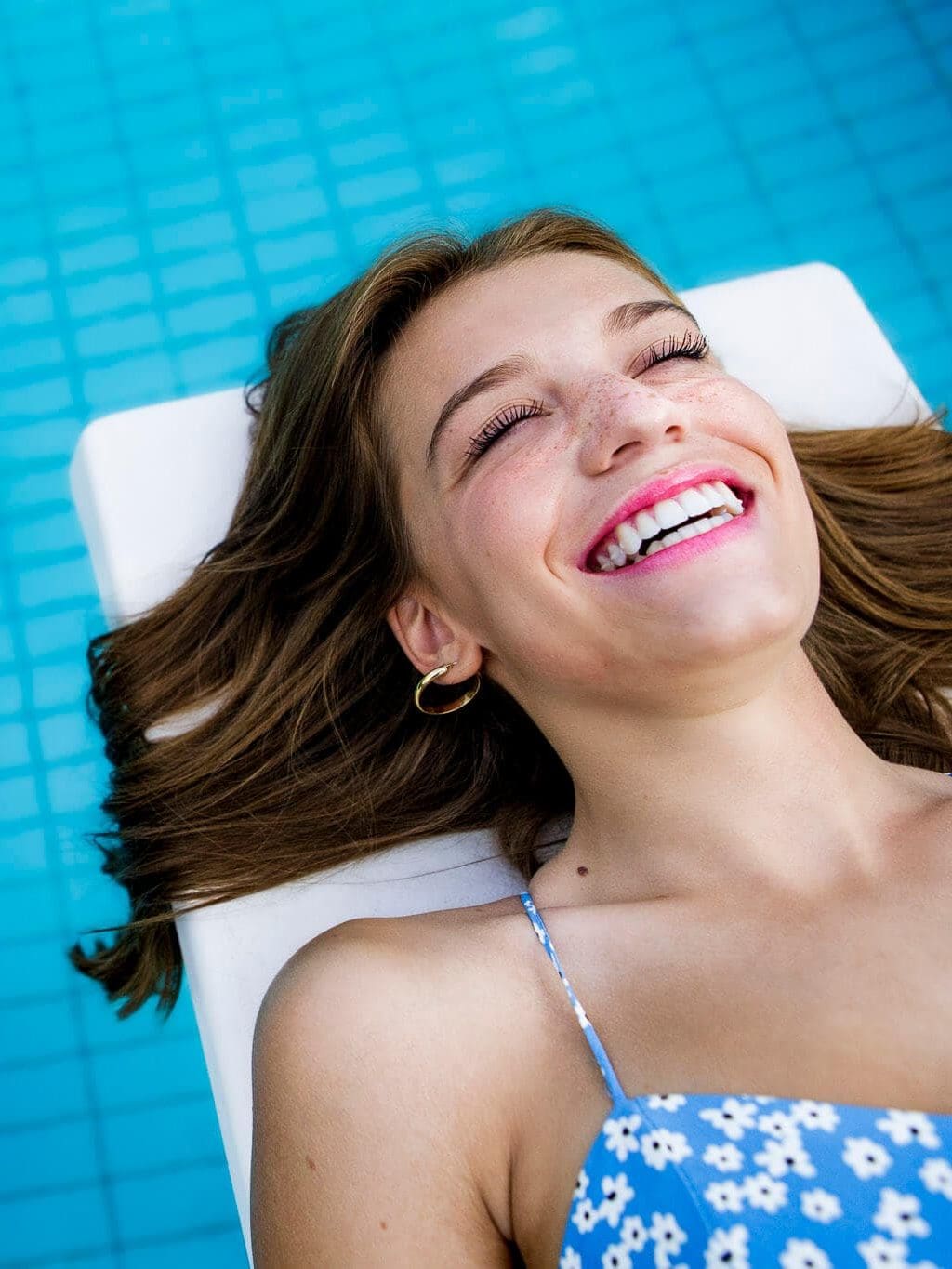 ragazza ride sdraiata sulla pedana sopra la piscina