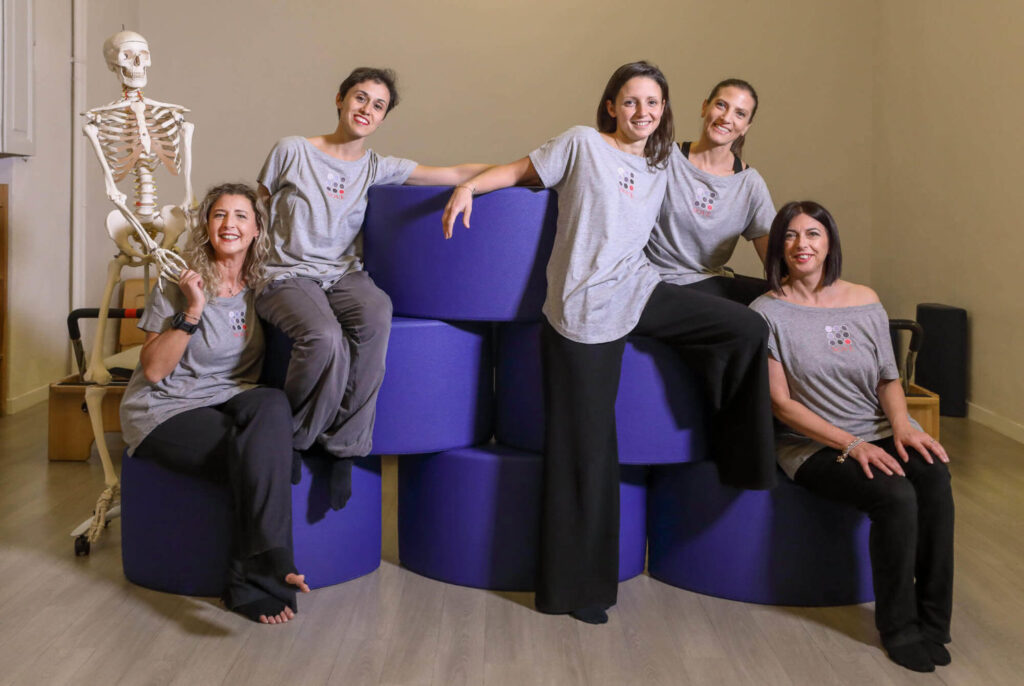 ritratto di gruppo delle trainers di pilates in palestra con attrezzi blu