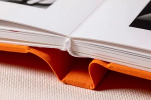 A detailed view of the spine and binding of an orange photo book. A detailed view of the spine and binding of an orange fine art photo album