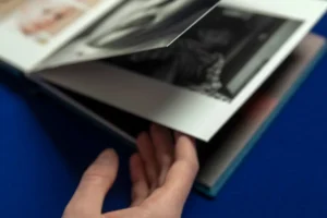 A close-up of a person’s hand flipping through the pages of a photo book. A close-up of a person’s hand flipping through a photo book filled with impactful photographs tailored to capture authentic moments and emotions.