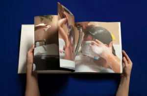 A person flipping through a photo book with images of children bathing. A person flipping through a photo book with images of children bathing.
