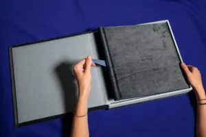 A person opening a velvet-textured box containing a special edition photo album. A person opening a velvet-textured box containing a special edition family photo album.