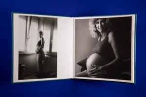 An open photo book displaying black-and-white maternity portraits of a pregnant woman. An open photo book displaying black-and-white maternity portraits of a pregnant woman.