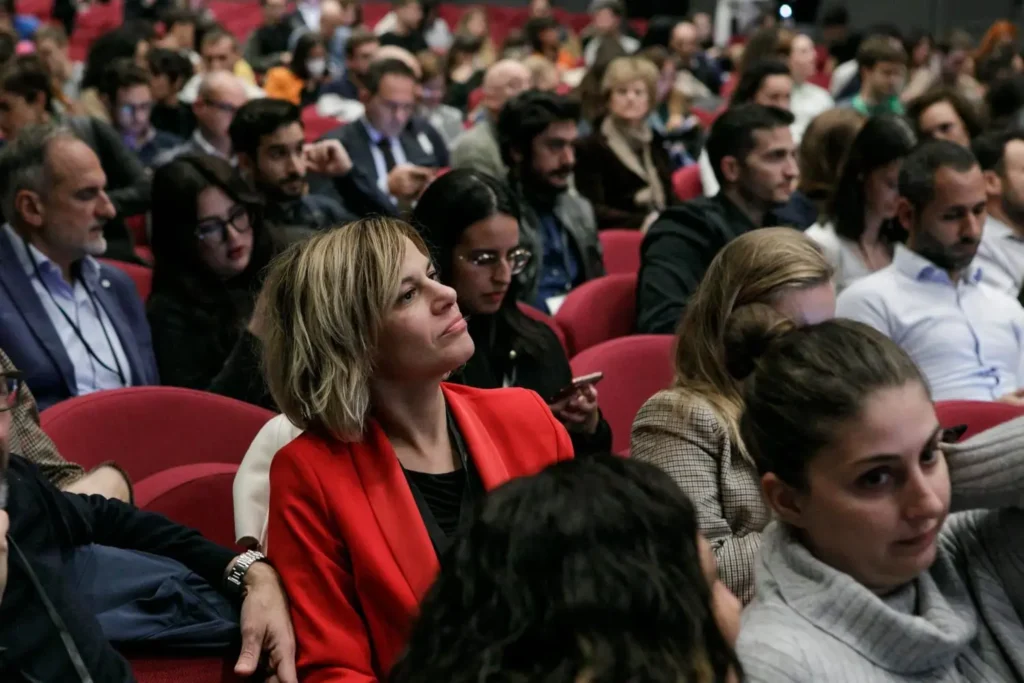 A diverse audience attentively listening at a conference in a large hall.