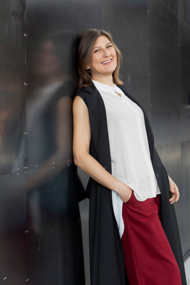 ritratto business professionale di donna in piedi appagiata alla parete di metallo