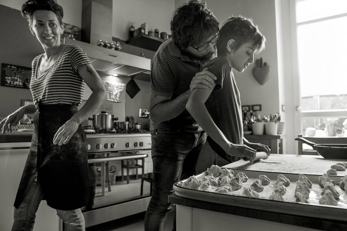 figlio con papa preparano i gnocchi con la mamma dietro